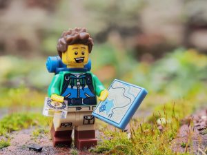 Photograph of an hiker made of lego carrying a lego map and compass.