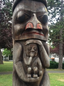 Section of Totem Pole, adult figure holding a child. 