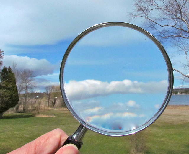 Magnifying glass held up to a countryside landscape
