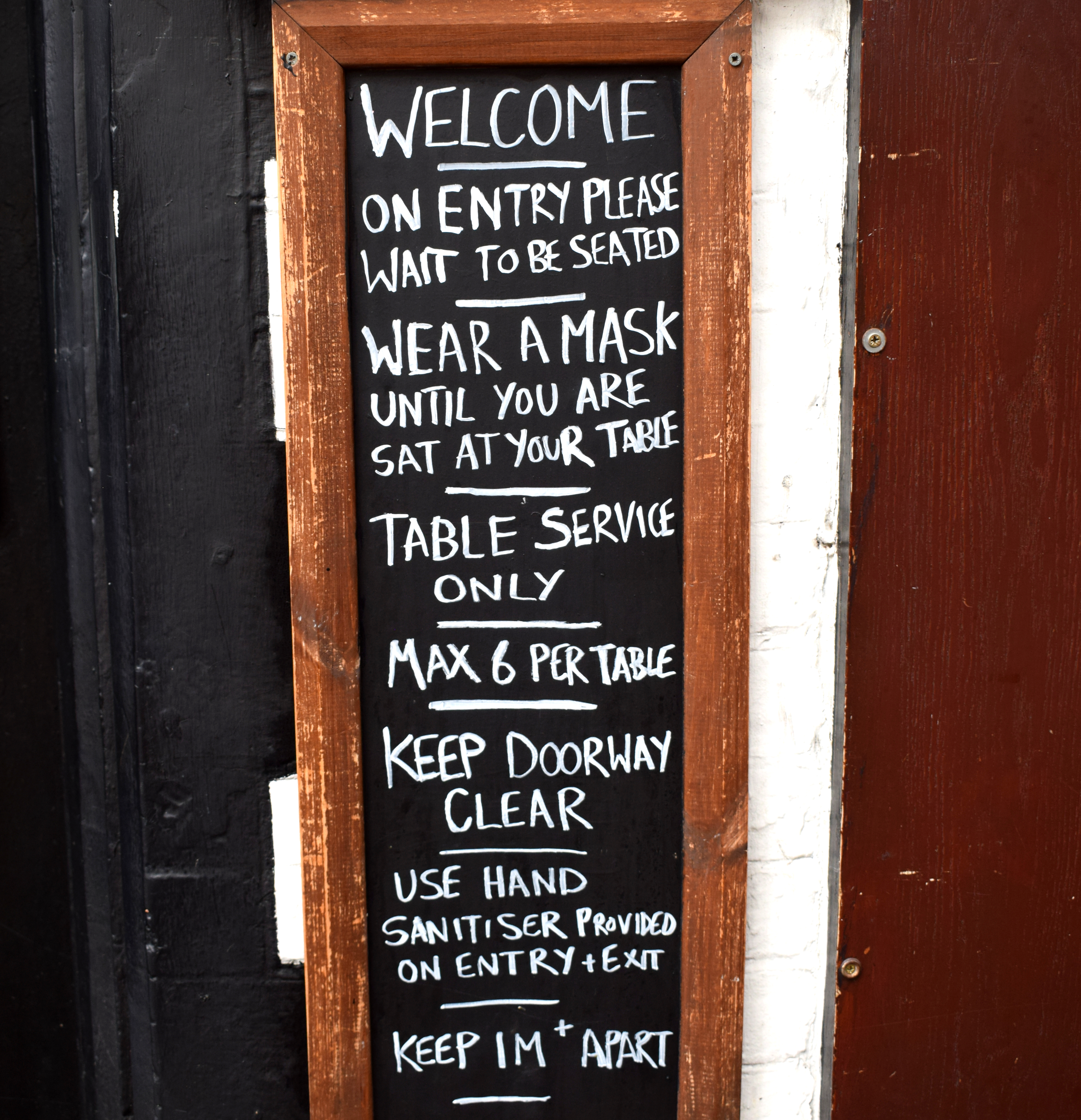 Picture A: a chalkboard showing covid rules for being in a bar, The Lady Luck, during tier 2.