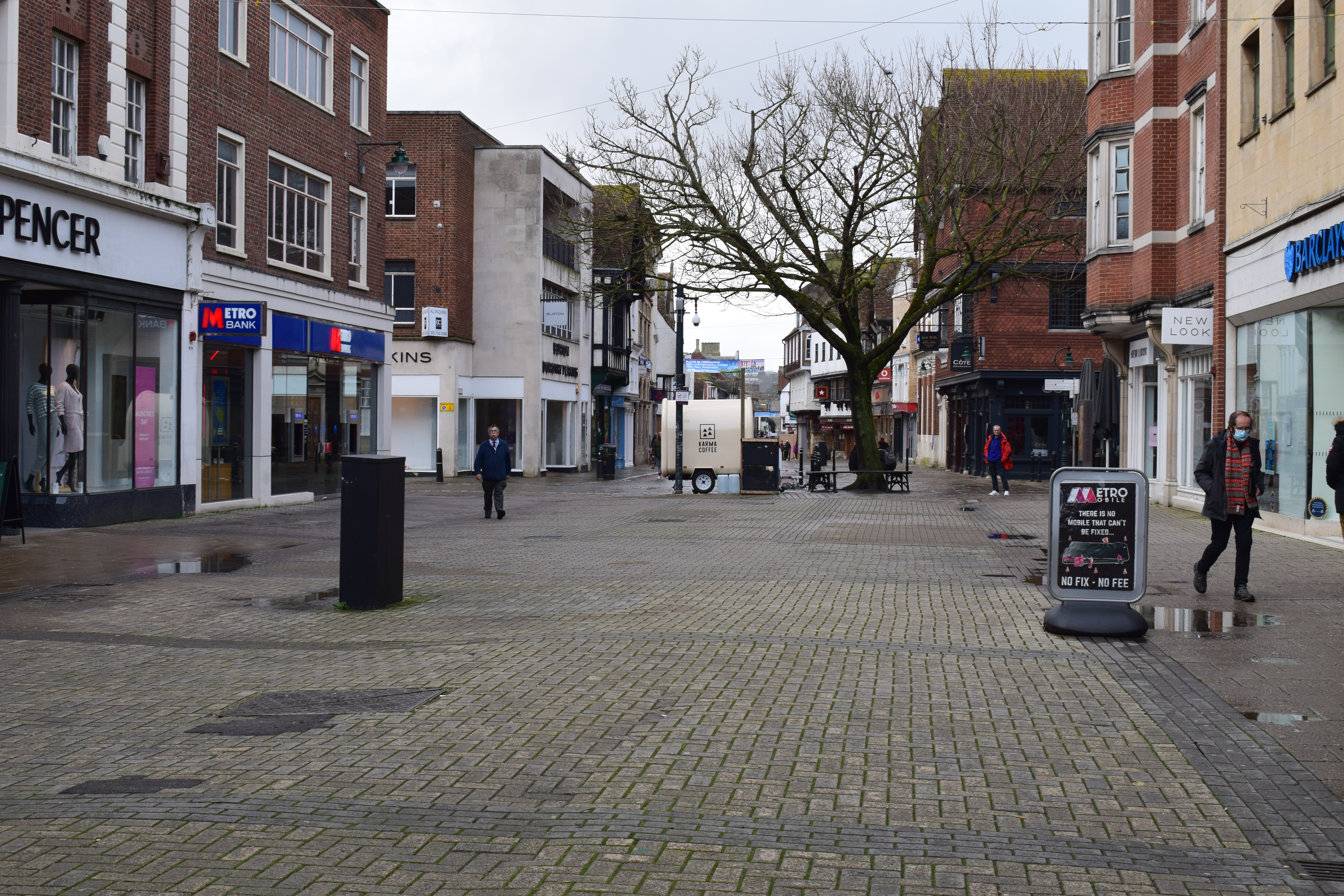 Picture C: Canterbury city centre, which is normally busy, entirely empty during the middle of the day. Some people are pictured, all wearing masks. 