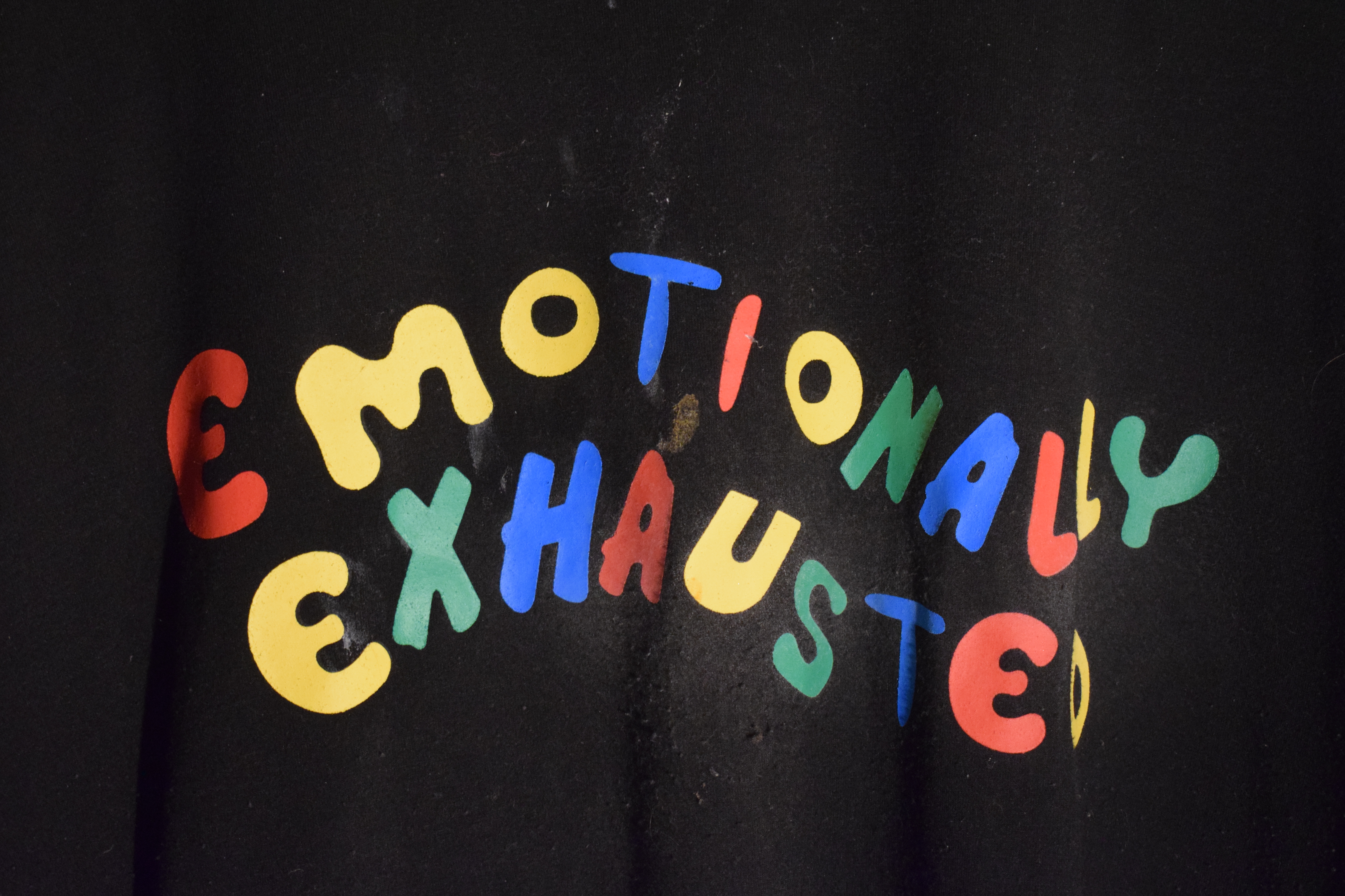 A dirty, stained black shirt with the phrase "emotionally exhausted" written across the front. 