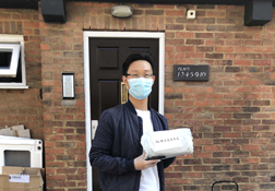 A UKC Chinese Society student wearing a mask and holding a care package