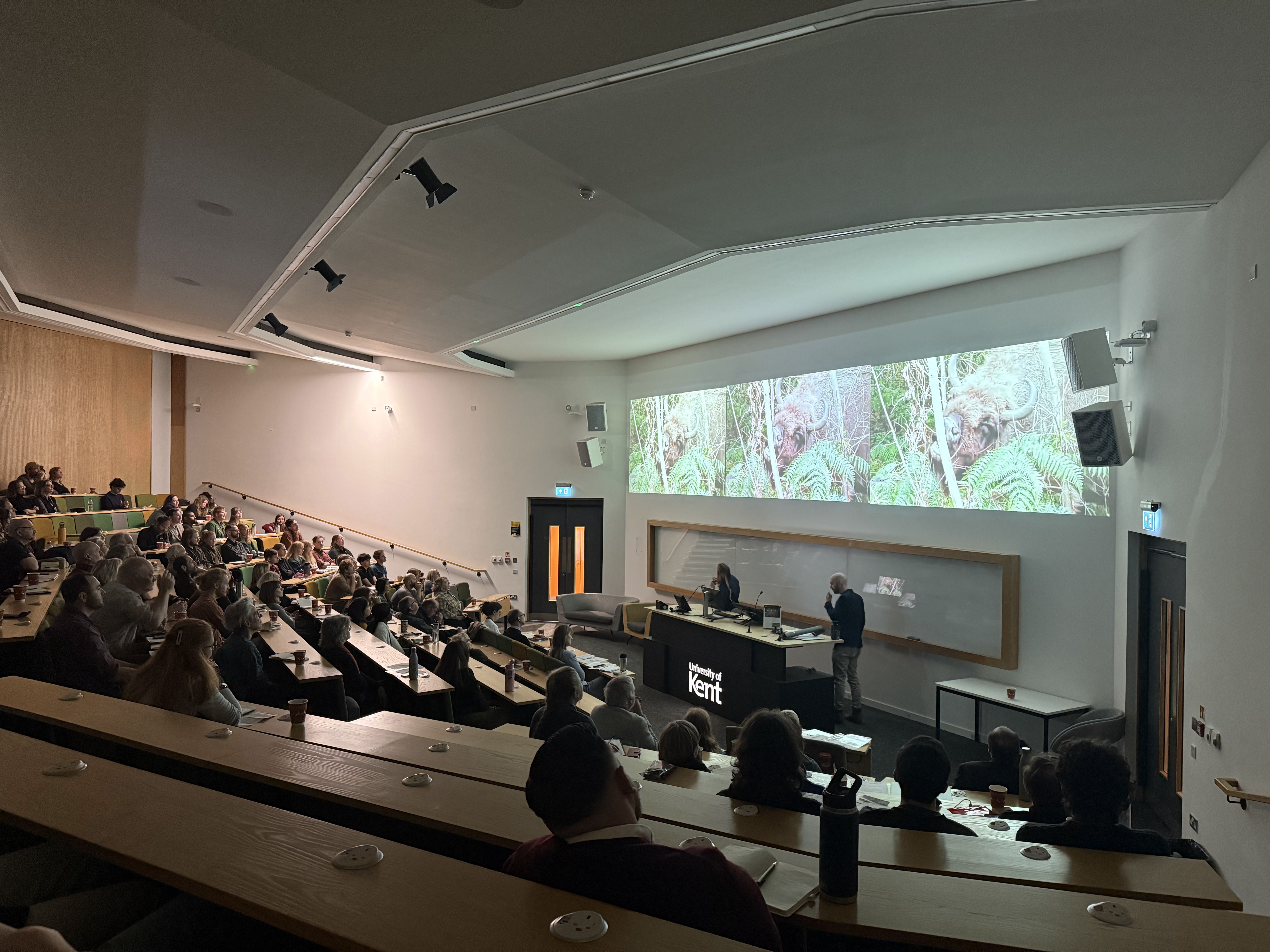 Lecture theatre full of attendees and two speakers at a lecturn