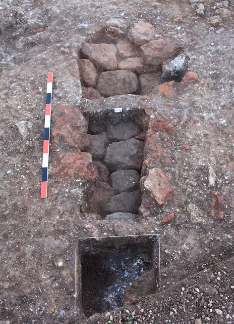 Corn-dryer showing flue mid-photograph, stoke-hole at bottom of picture, partly excavated