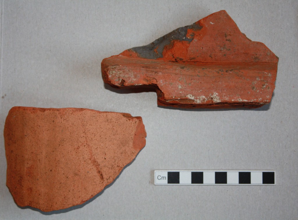 Two fragments from Roman roof tiles. The fragment on the right comes from the broad flat type (known as tegulae) which would have covered most of the roof area. This example shows traces of mortar for attachment of the arched tile type (known as imbrices) which sealed the joins between tegulae. Presumably our mortared example here had been used for roofing at our site.
