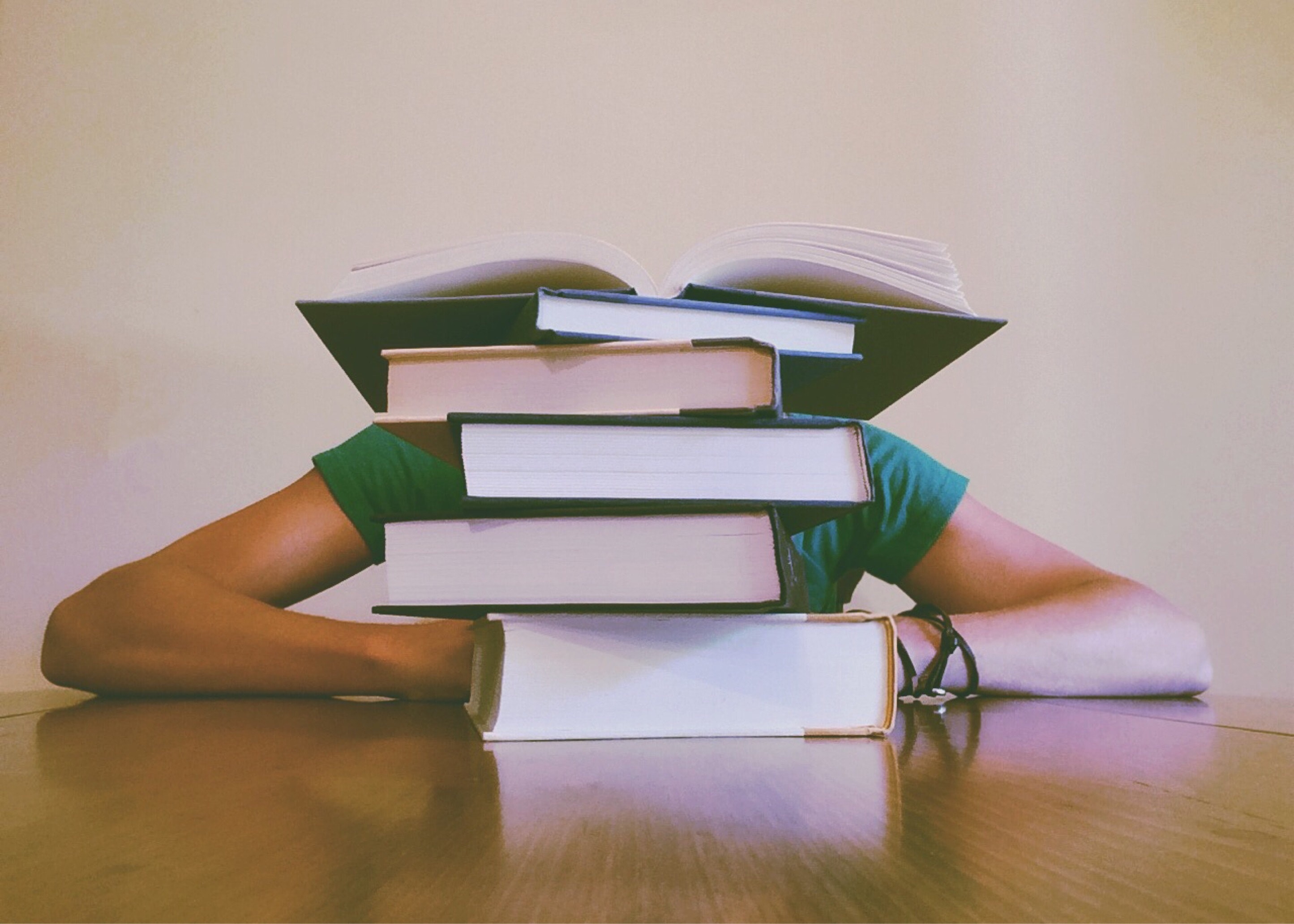 A person sitting behind a pile of books