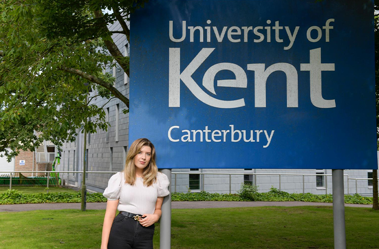 A picture of ruby by the Kent sign outside Canterbury Campus