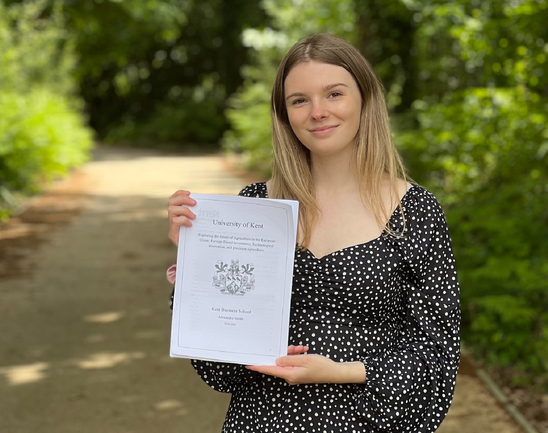 Alex holding her 1st Class dissertation with pride