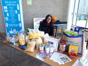 A student volunteer waits at a table laden with food donations for the Fare Share charity. 