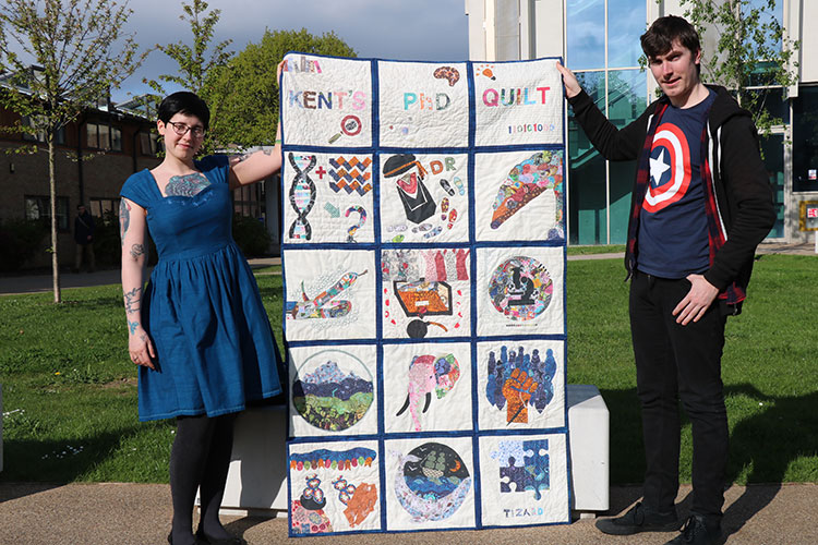 Laura Thomas-Walters holding the Kent PhD quilt with fellow DICE student Steven Allain