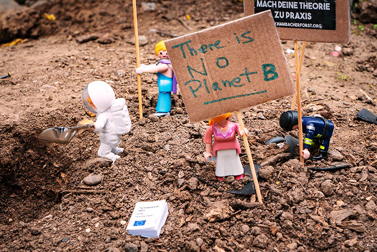 Toy figures in soil holding placards emblazoned with 'There is no Planet B'