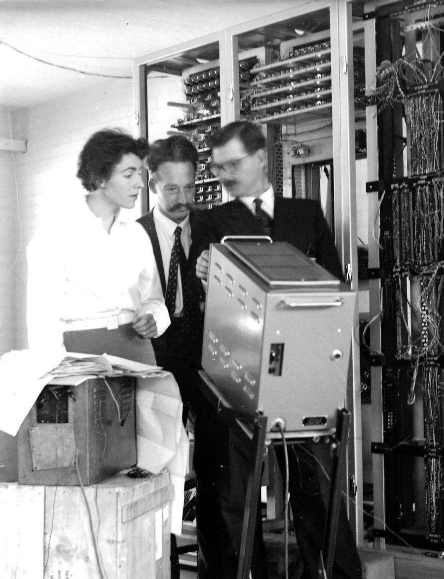 Dame Stephanie on the far left with two male colleagues look at the screen of a piece of computer equipment in approximately 1957