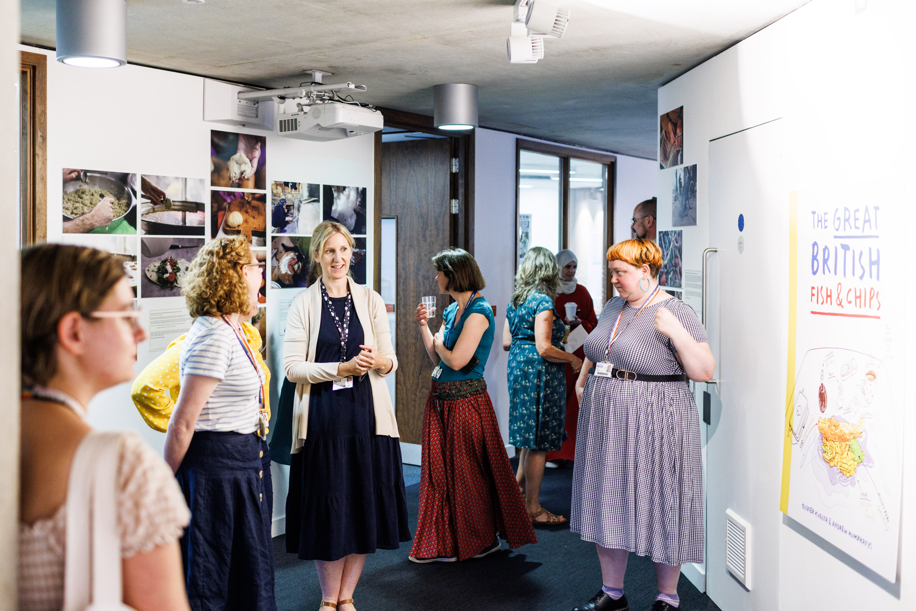 A photograph of a small group of people standing in the Templeman Library gallery space, looking at the exhibition. 