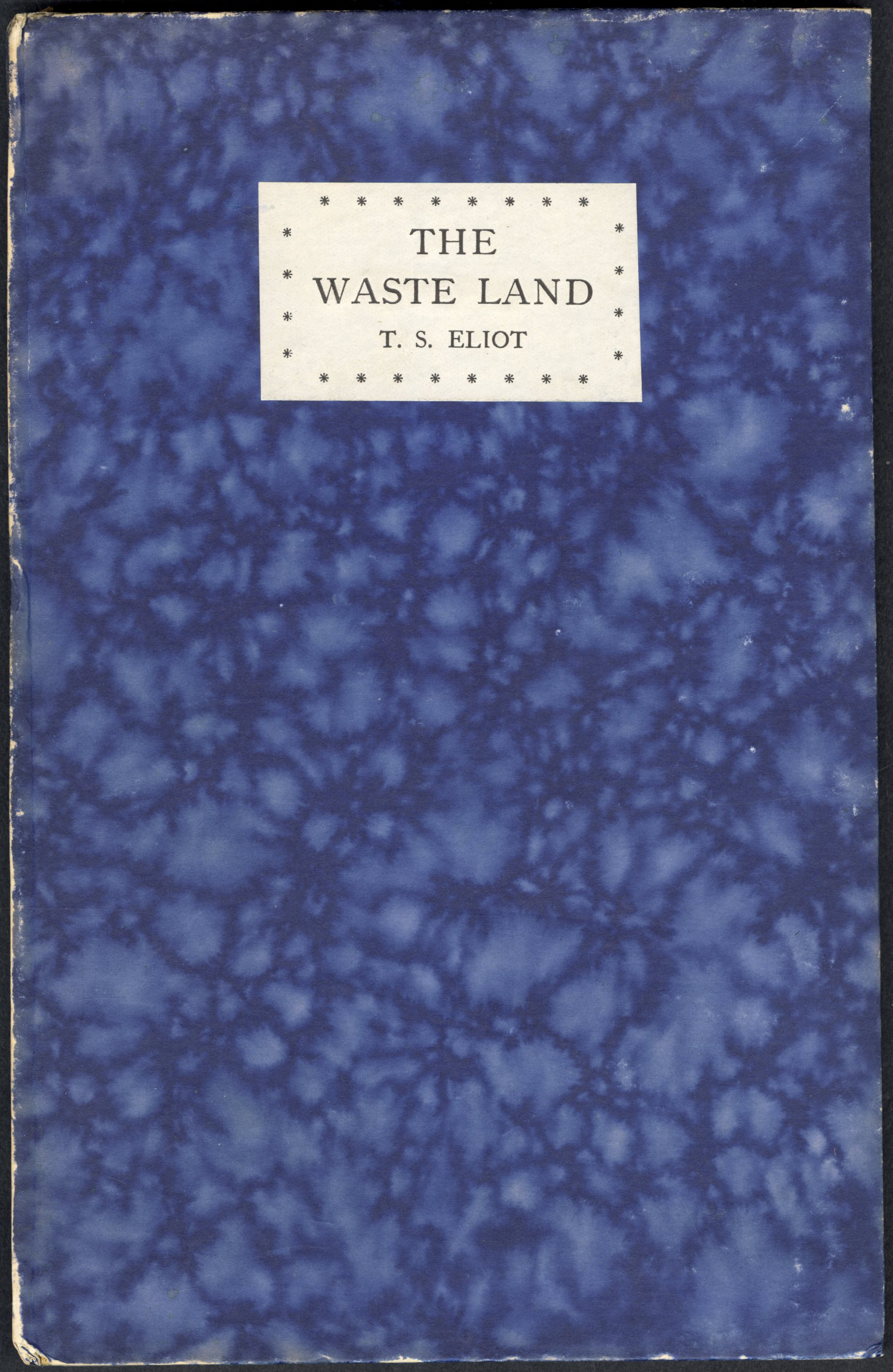 Image of front cover of the first edition of The Waste Land by T.S Eliot - which has blue marbled cover papers 