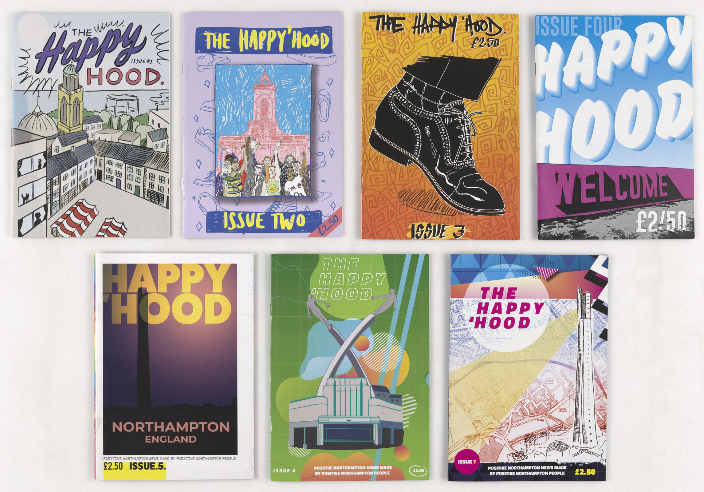 A photograph of 7 issues of Happy Hood zine, their covers facing the viewer. 