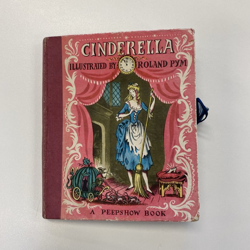 Picture of the front cover of Roland Pym's Cinderella, depicting the heroine in rags holding a broom.