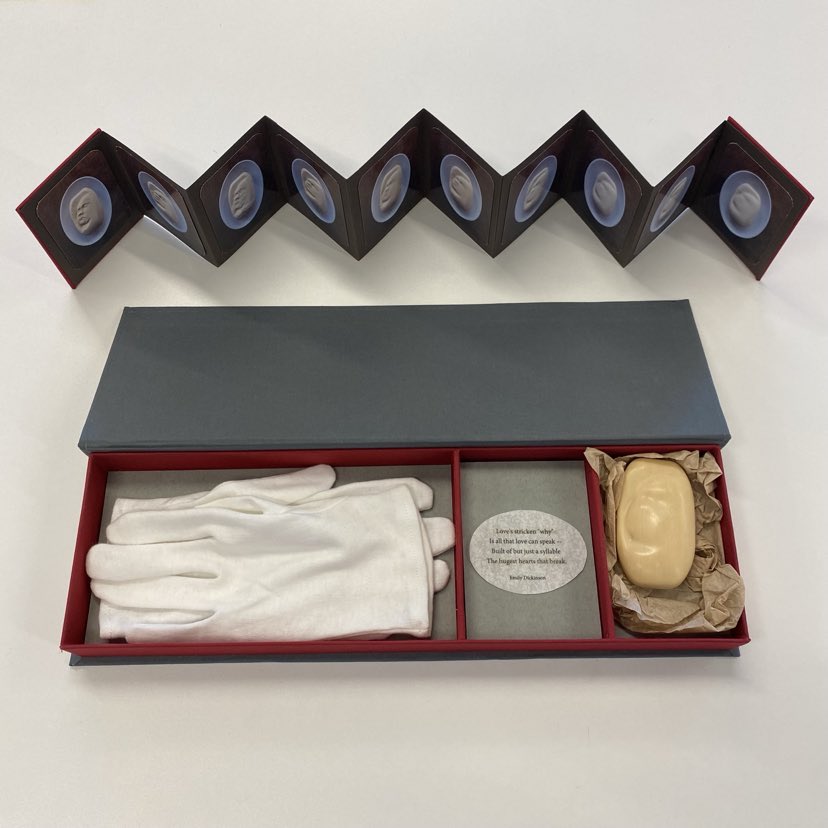 picture of Karen Apps' Losing Touch, which takes the form of a concertina book inserted into a box alongside a pair of white gloves and a partially eroded sculpted soap bar.