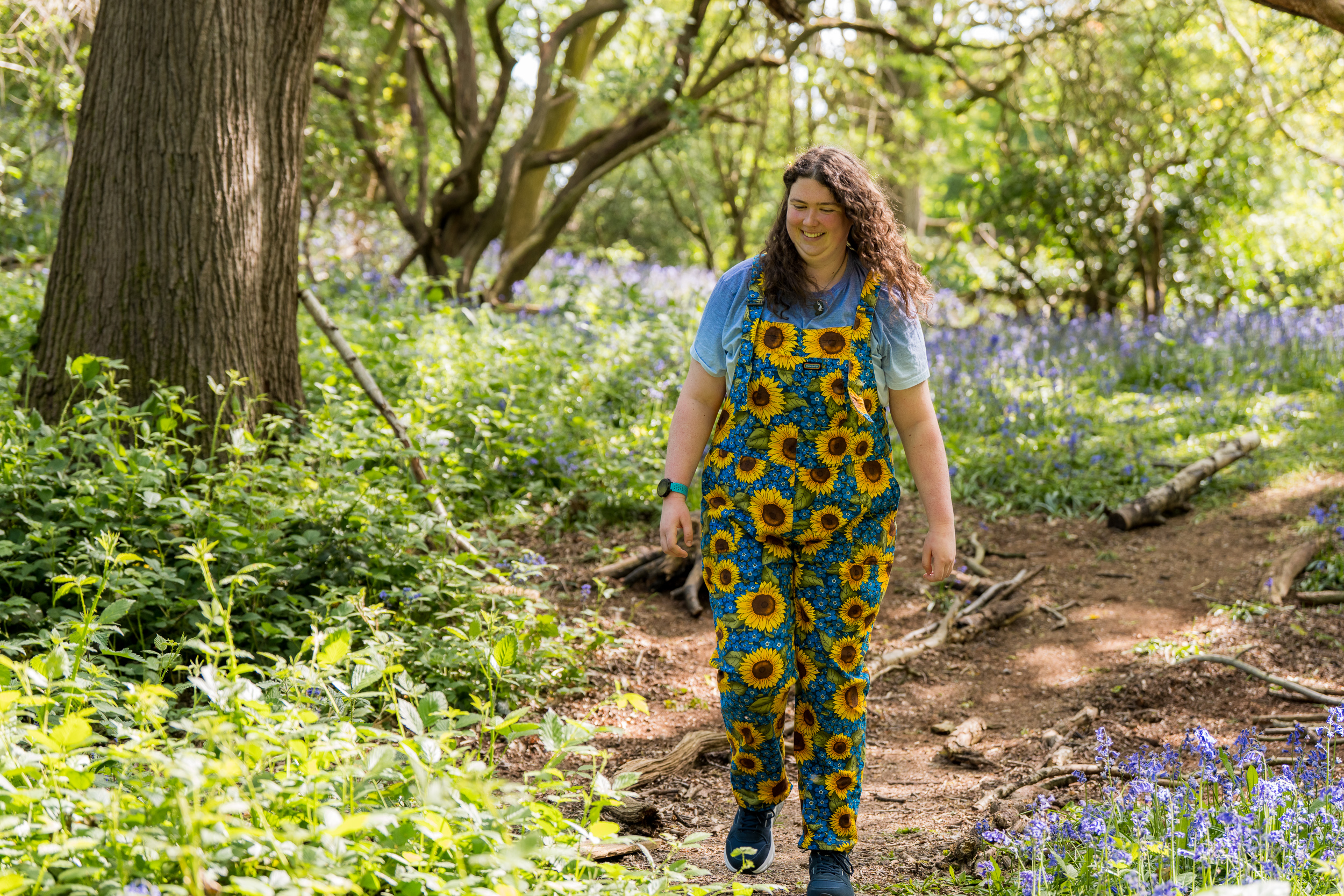 Elinor smiling walking through bluebells on campus