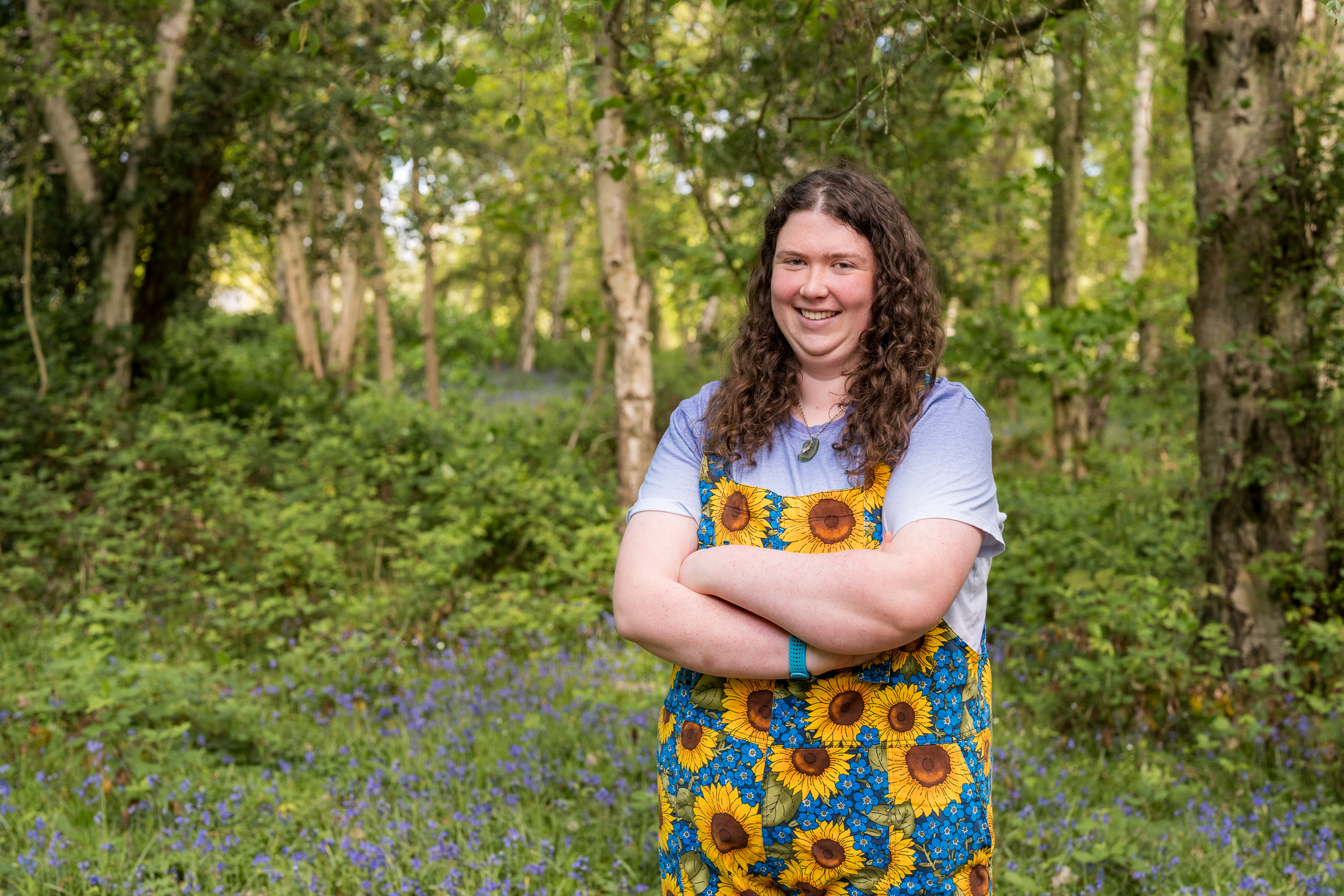 Elinor smiling with her arms crossed with bluebells behind her