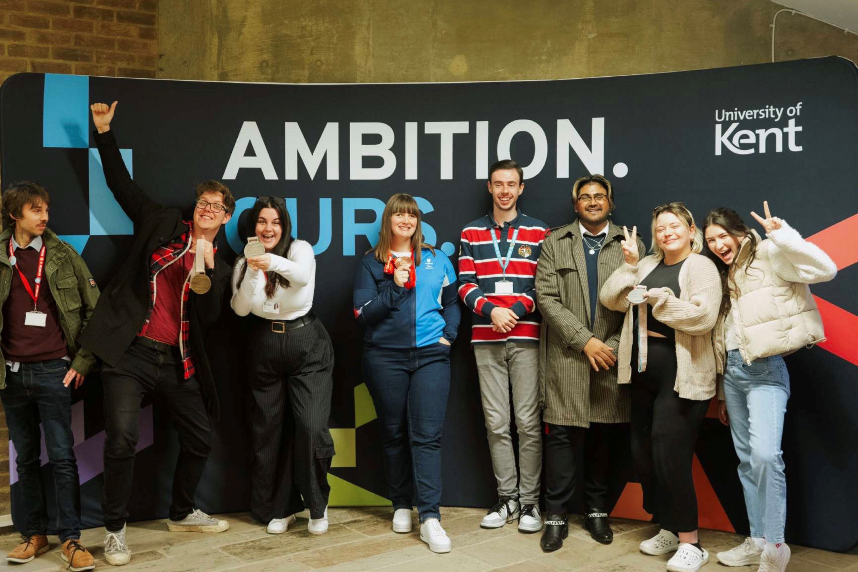 Group of people standing in front of a banner, holding medals.