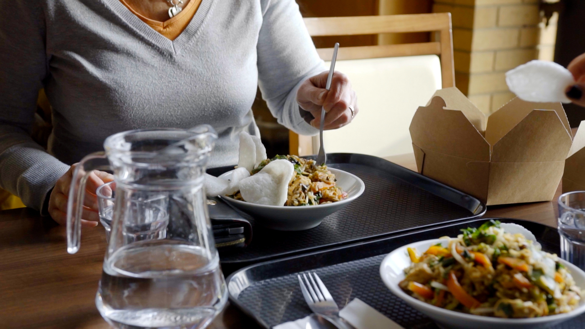 Two people dining in Rutherford Dining Hall, enjoying stir fry noodles from the Wok Bar