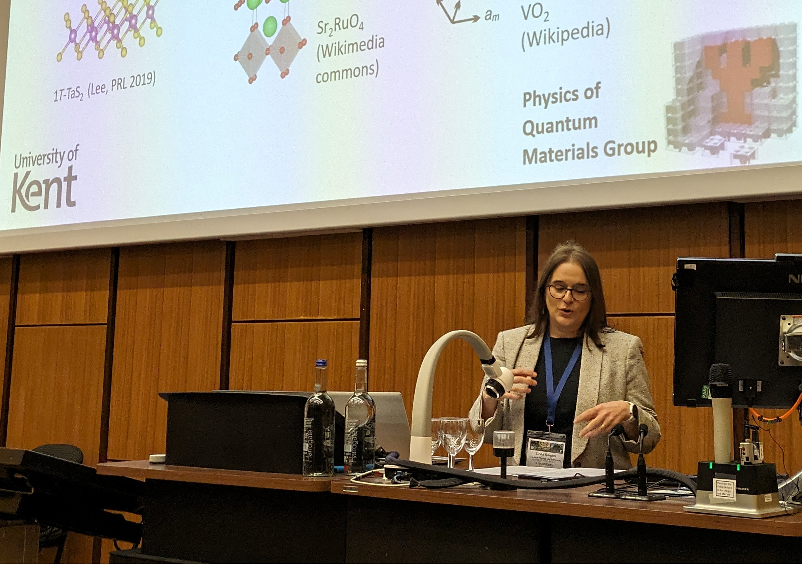 Silvia presenting at in a lecture theatre with a powerpoint presentation behind them