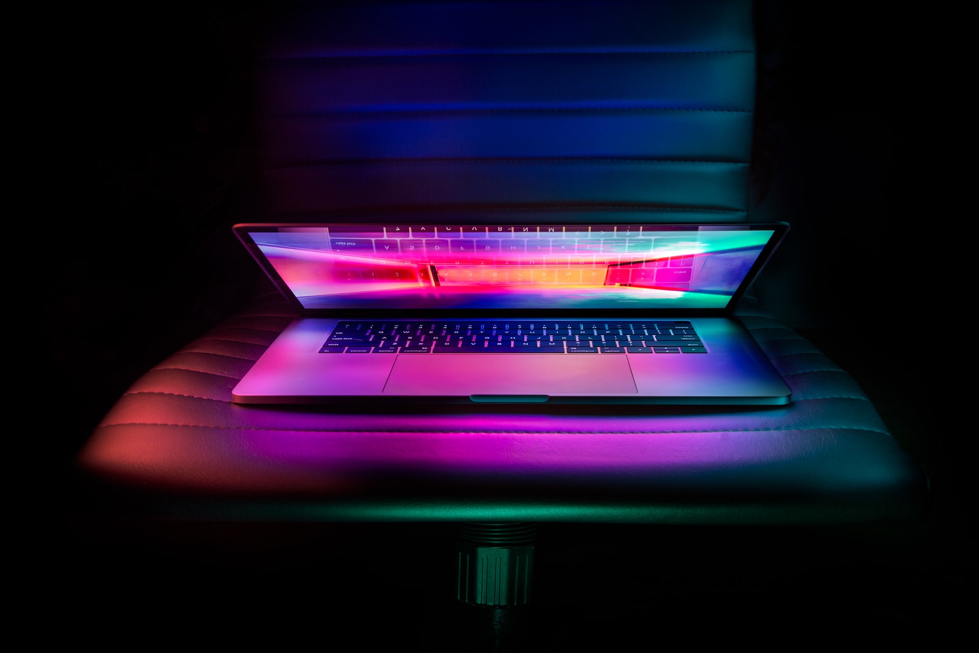 Open laptop with bright multicoloured screen on black office chair