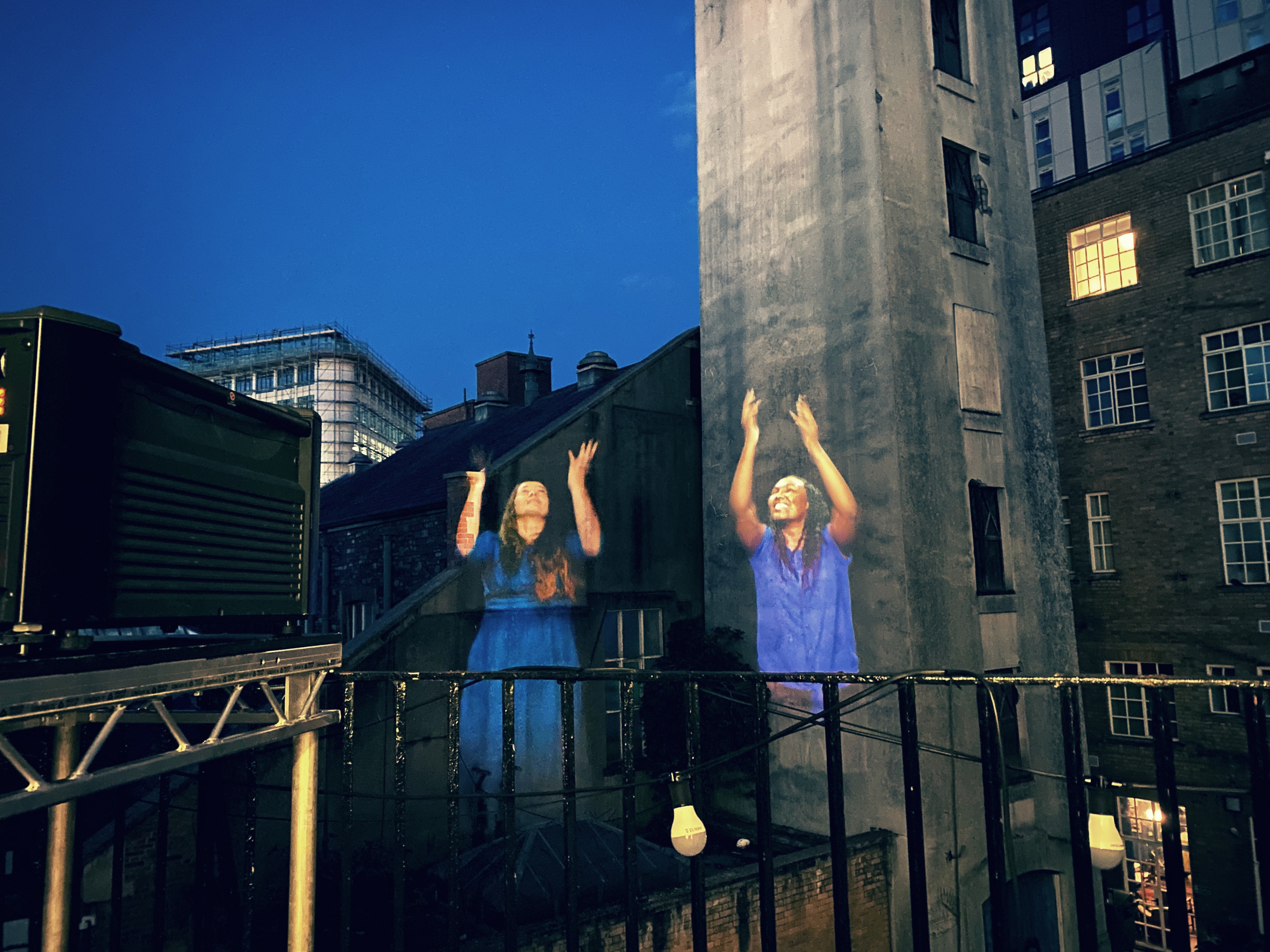 Images of two women projected onto an urban background