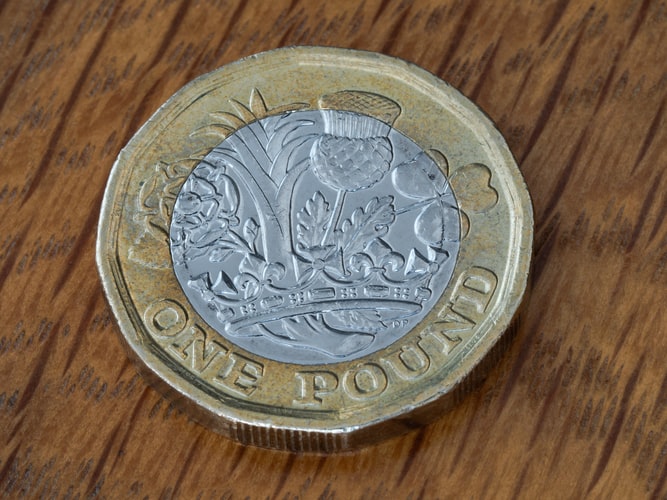 One British Pound on a wooden table
