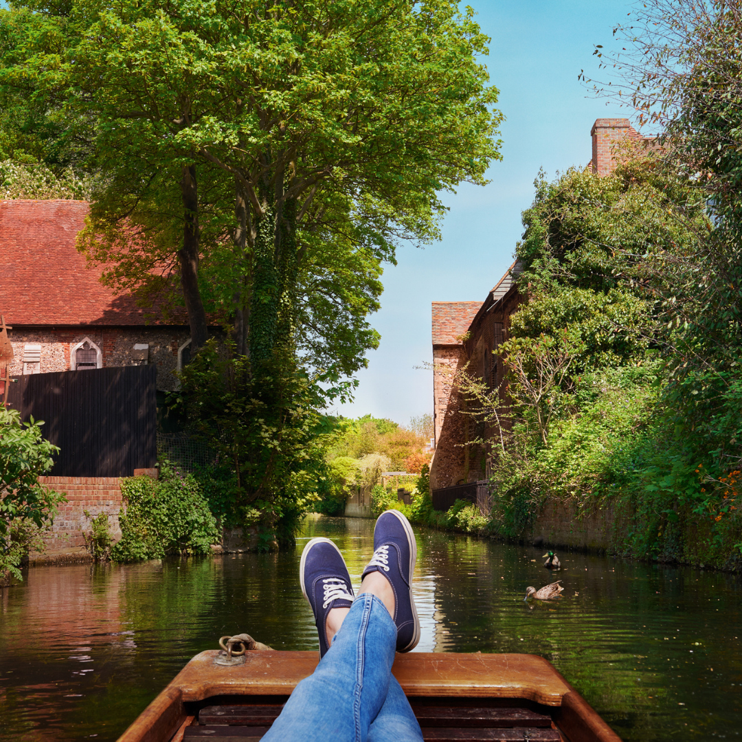 A view of the River Stour from a boat with someone's shoes in the foreground