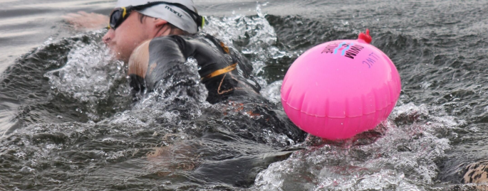 An open water swimmer and pink inflatable