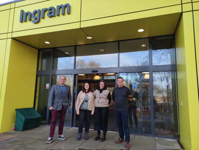 Rob, Alix, Chloe and Jon pose outside the yellow Ingram Building on campus