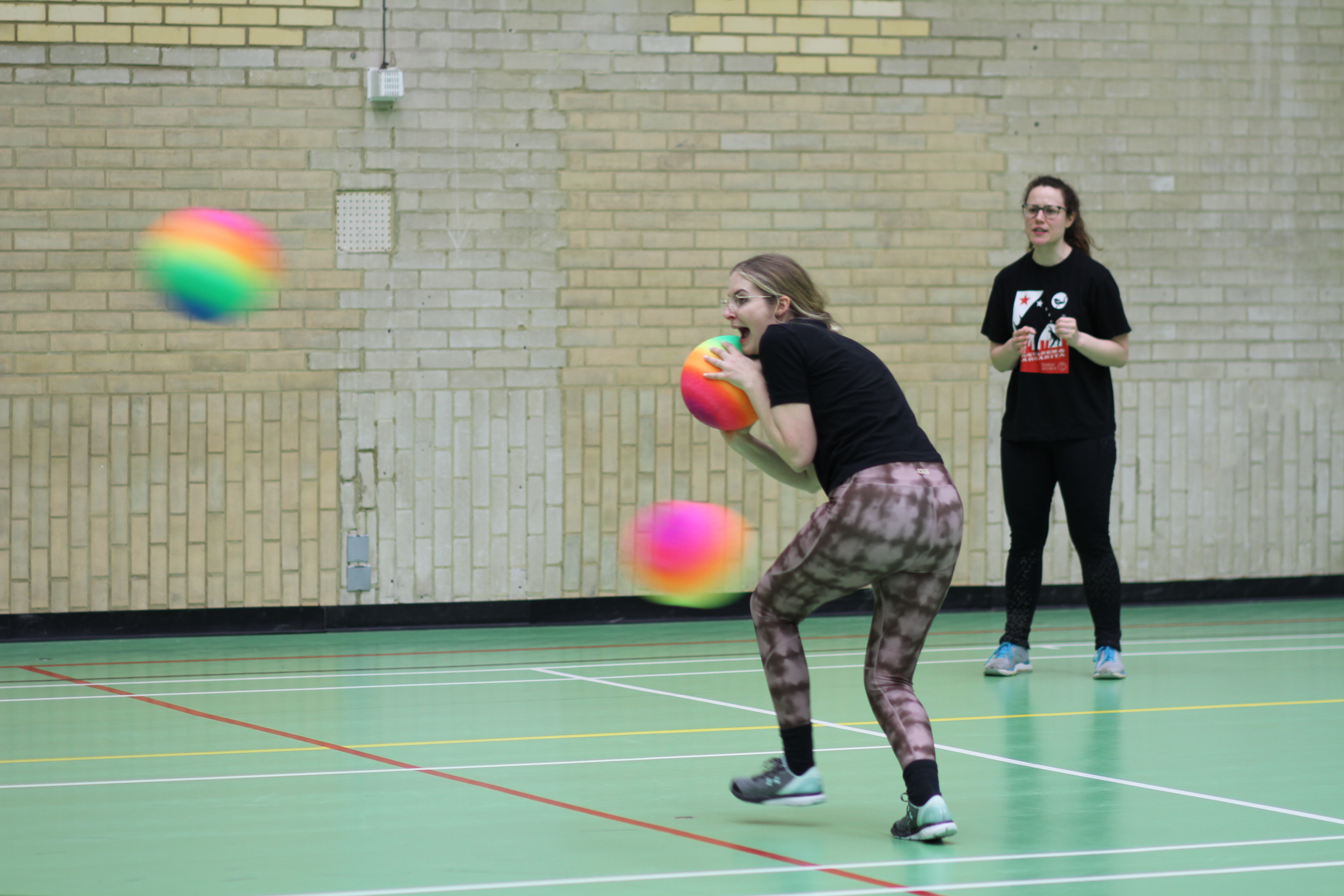 Player ducking and trying to get away from three dodgeballs which have been thrown at her.
