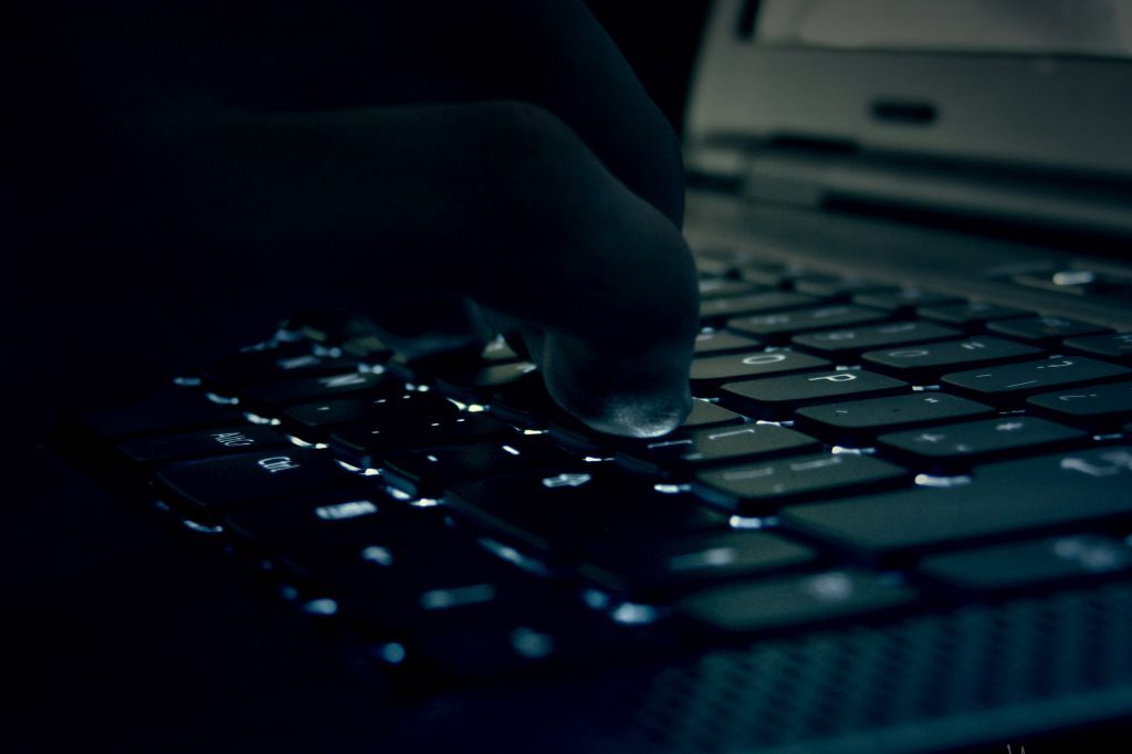 Hand typing on keyboard in dark room