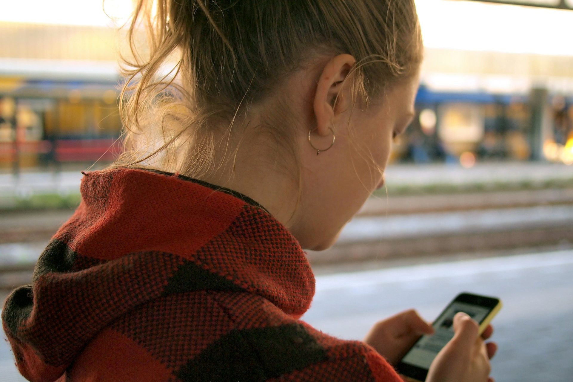 A woman at a train station looking down at her phone