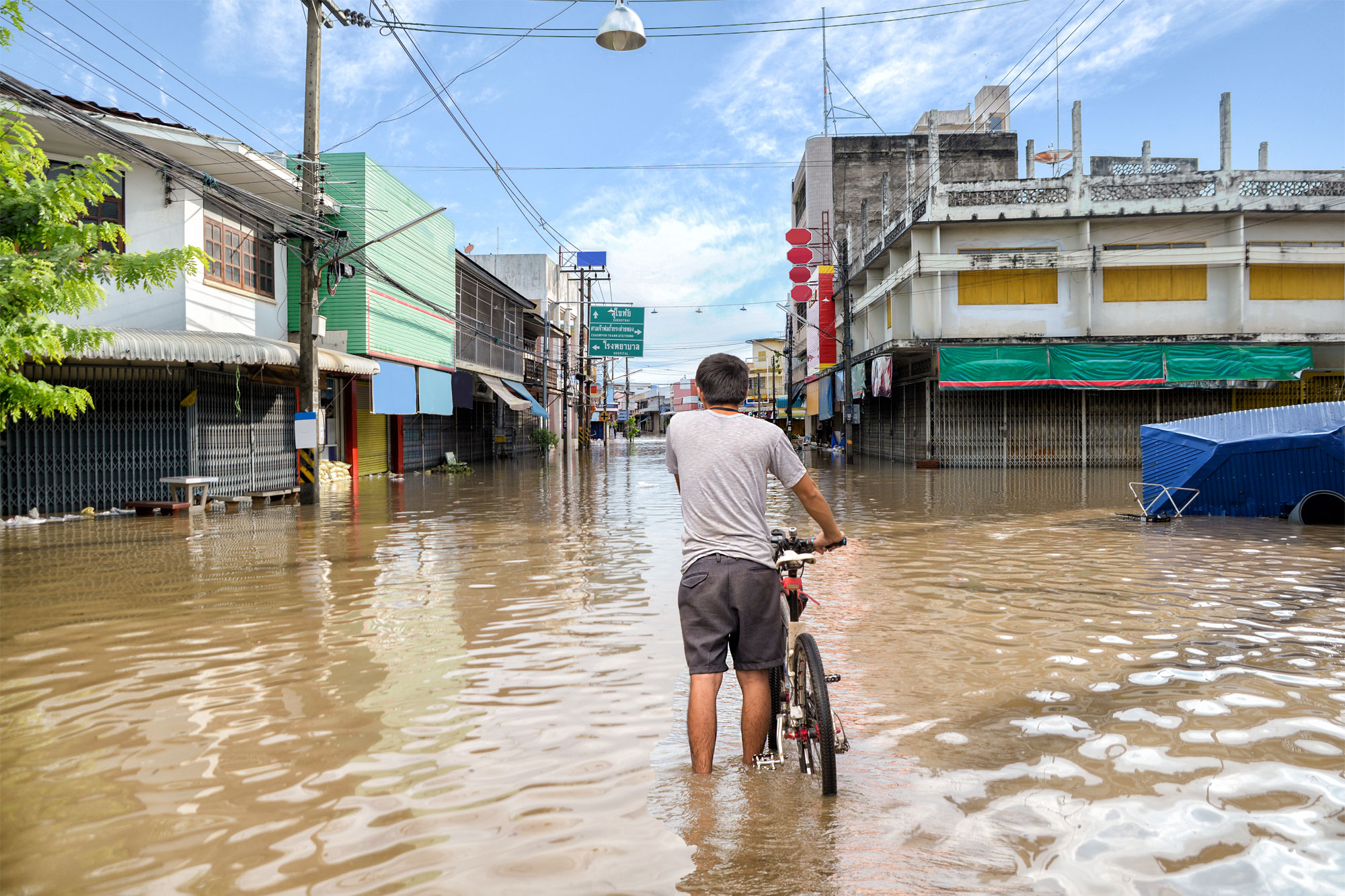 Man with bicycle standing in flooded crossroads in urban space