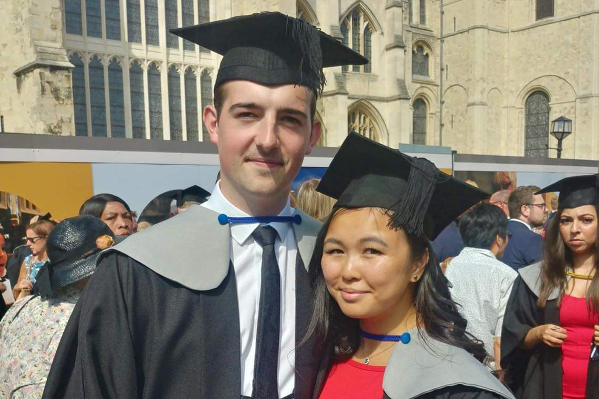 Cameron and Josephine outside Canterbury Cathederal wearing graduation gowns and mortar boards