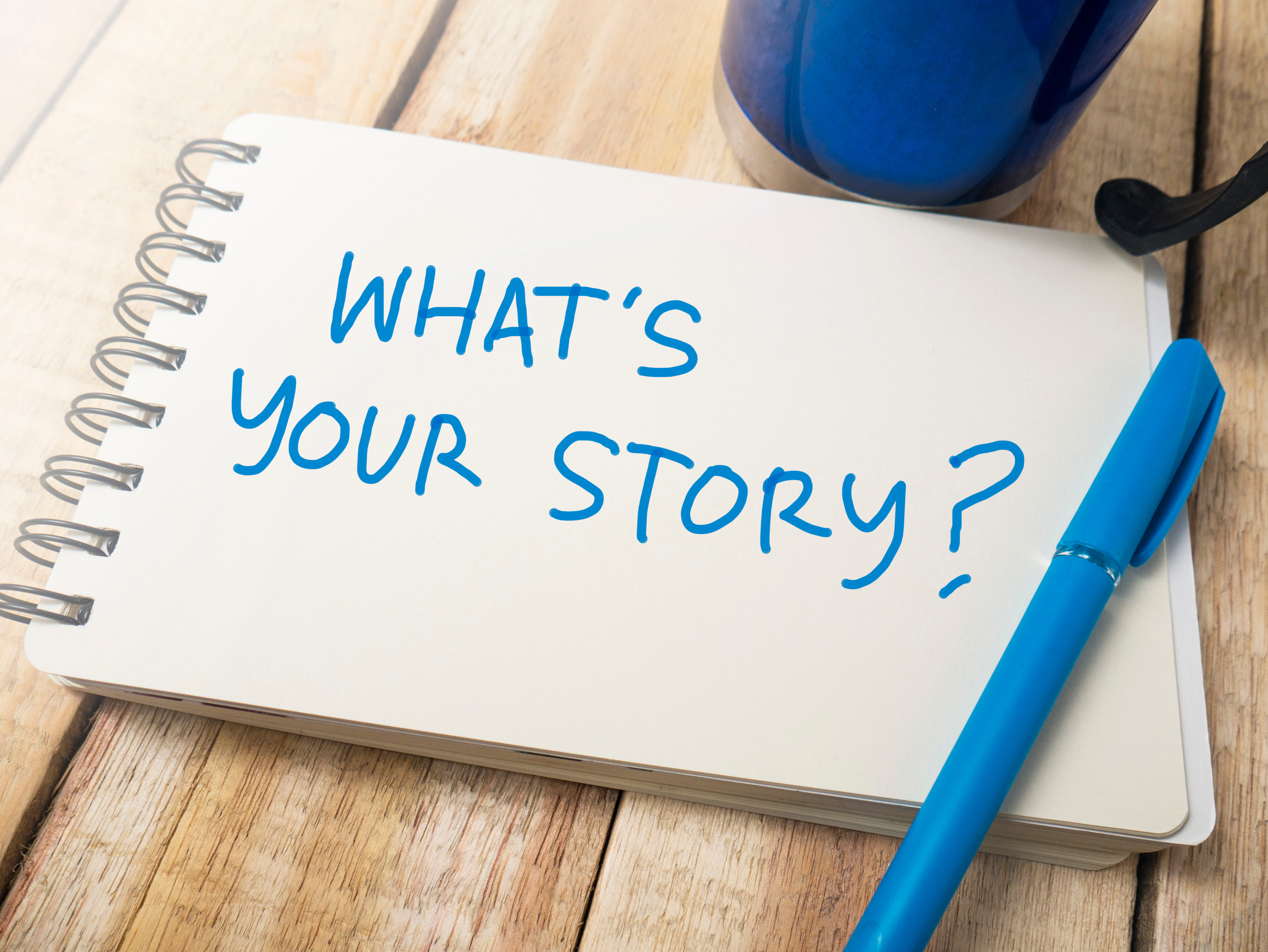 What's your story? is written on a plain notepad in blue ink.