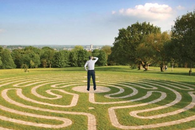 Man standing in the middle of a field at the University of Kent facing towards the landscape of Canterbury