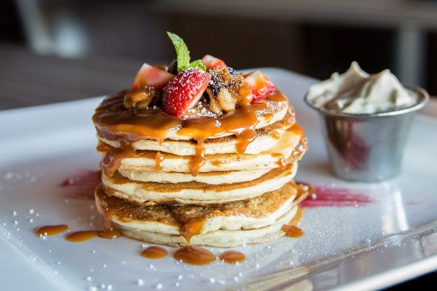 A stack of pancakes with fruit and maple syrup