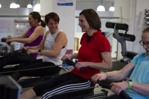 Vice Chancellor Karen Cox and three other female employees all on rowing machines taking part in the Row Britannia challenge