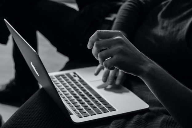 Black and white photo of hands tying on laptop