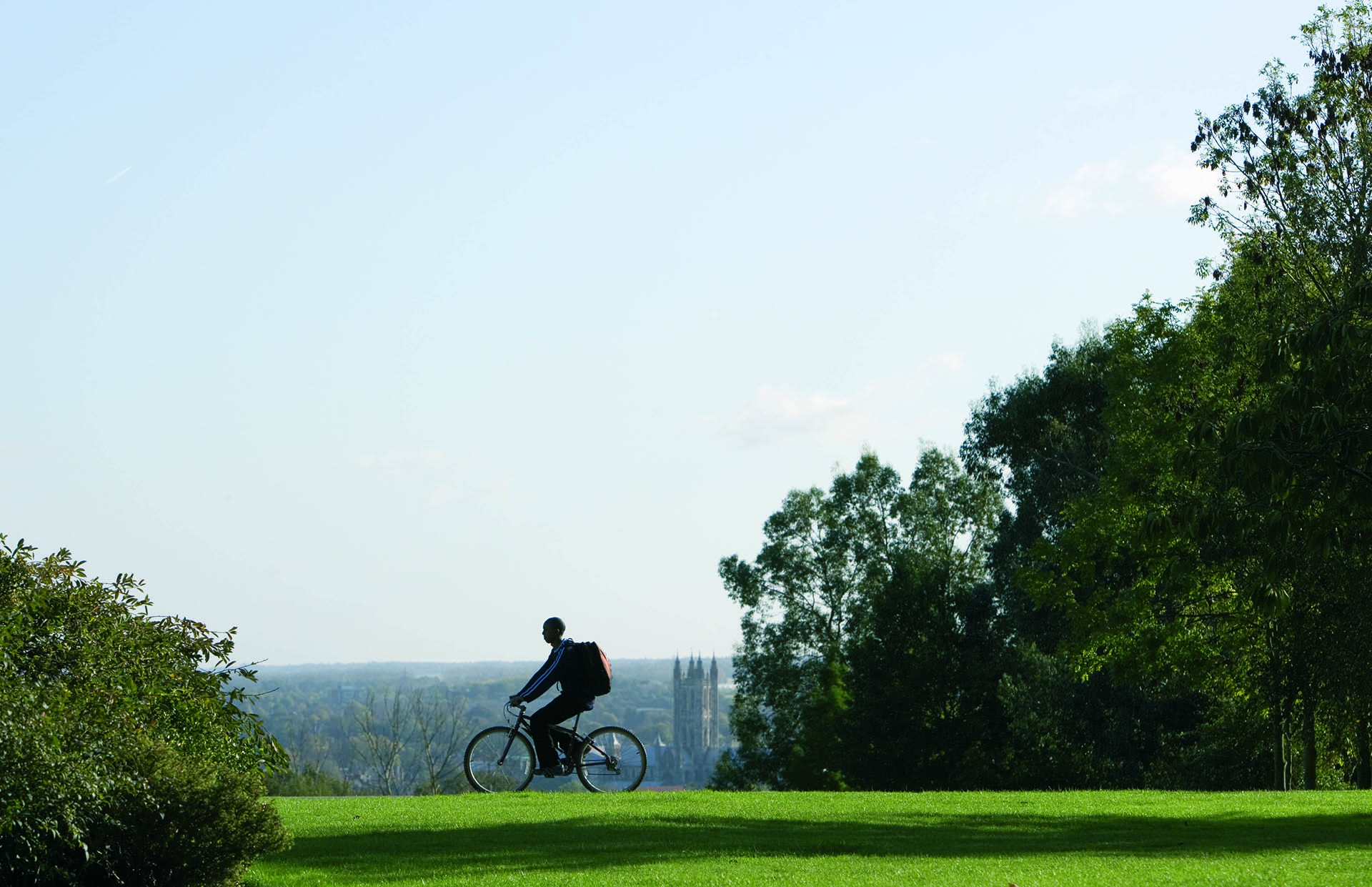 Man cycling on Canterbury campus with Canterbury cathedral in background