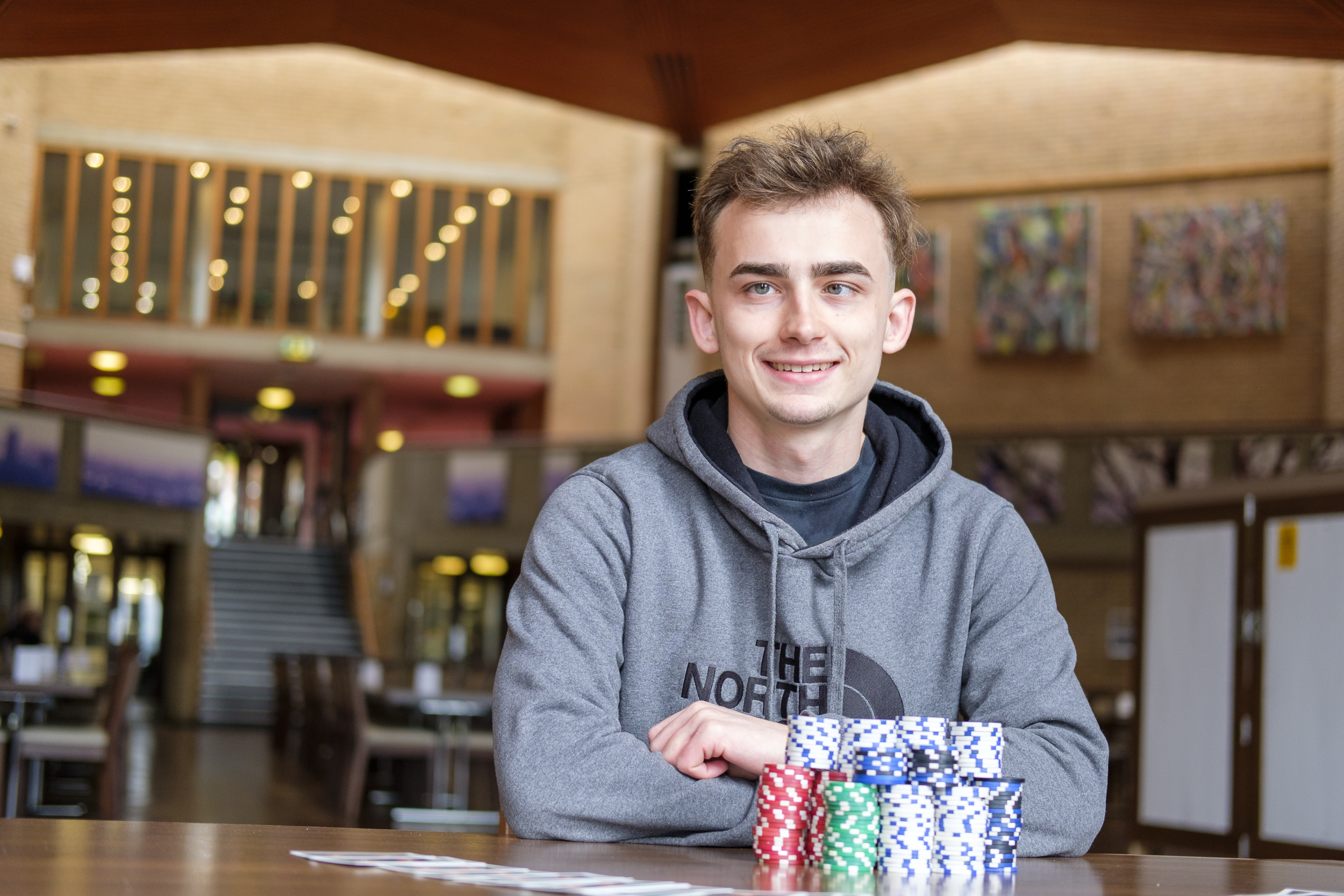 Student Lewis Powell smiling with poker chips on table in front of him