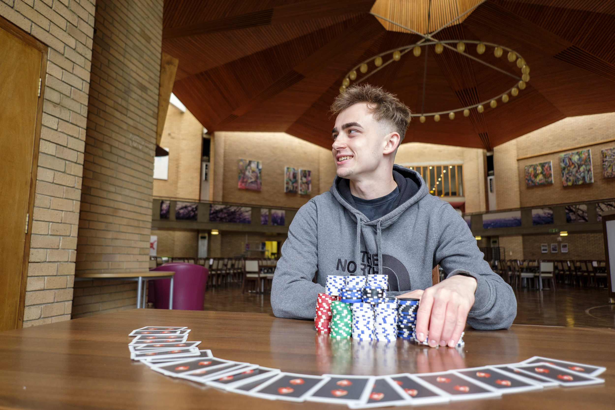 Student Lewis sat at table with playing cards and poker chips