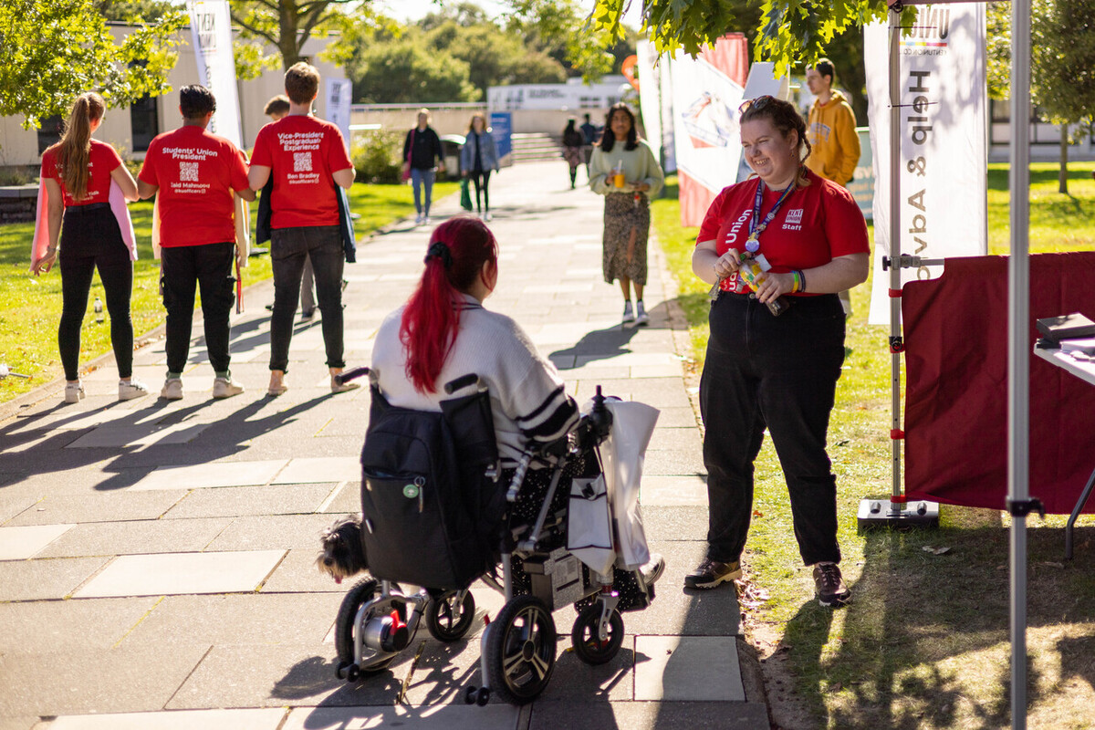 Student in a wheelchair talking to Kent Union staff