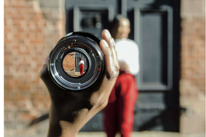 foreground lens focusing on out of focus person in the background standing in front of a doorway in a brick wall