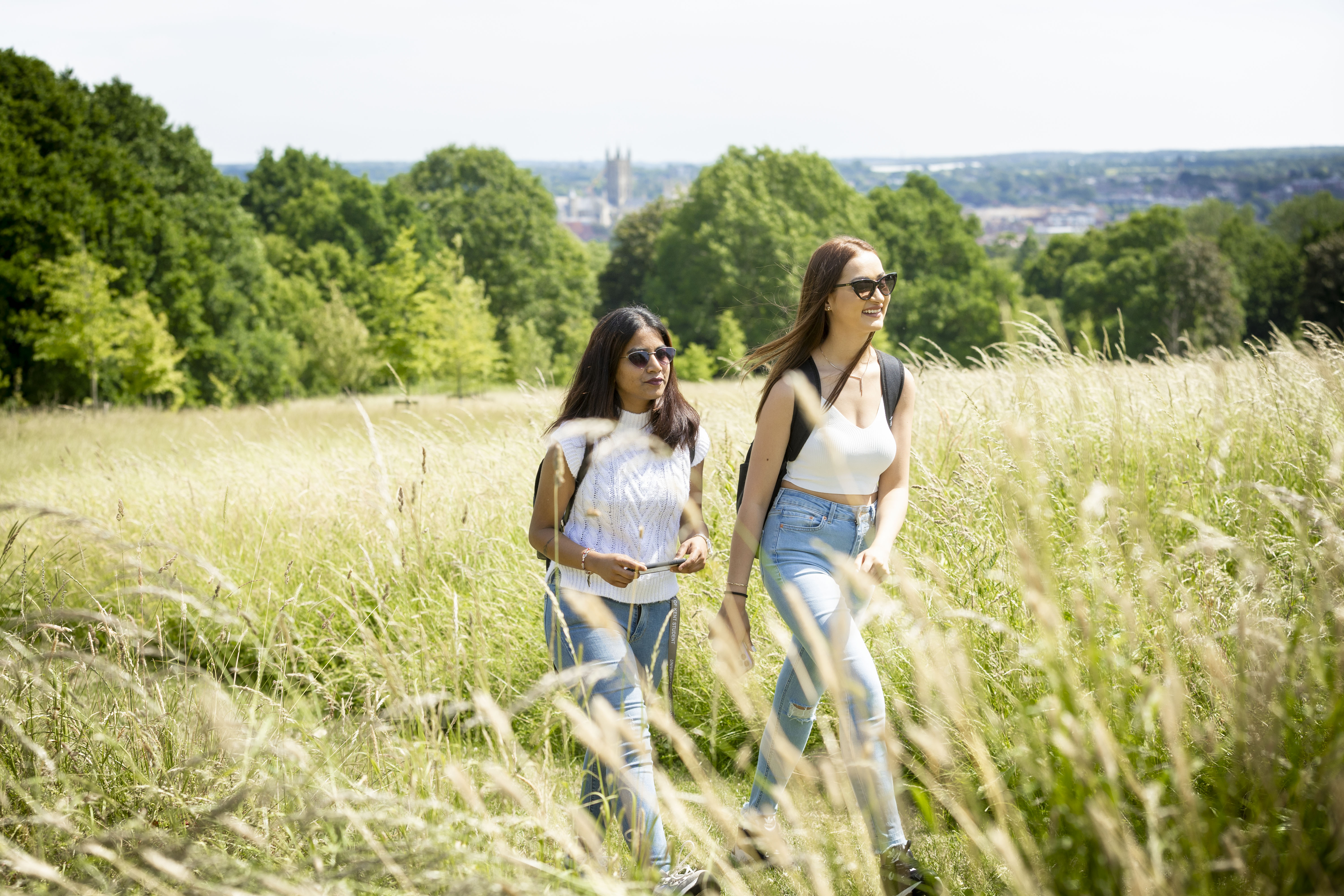 Two students walking through field with canterbury cathedral in background