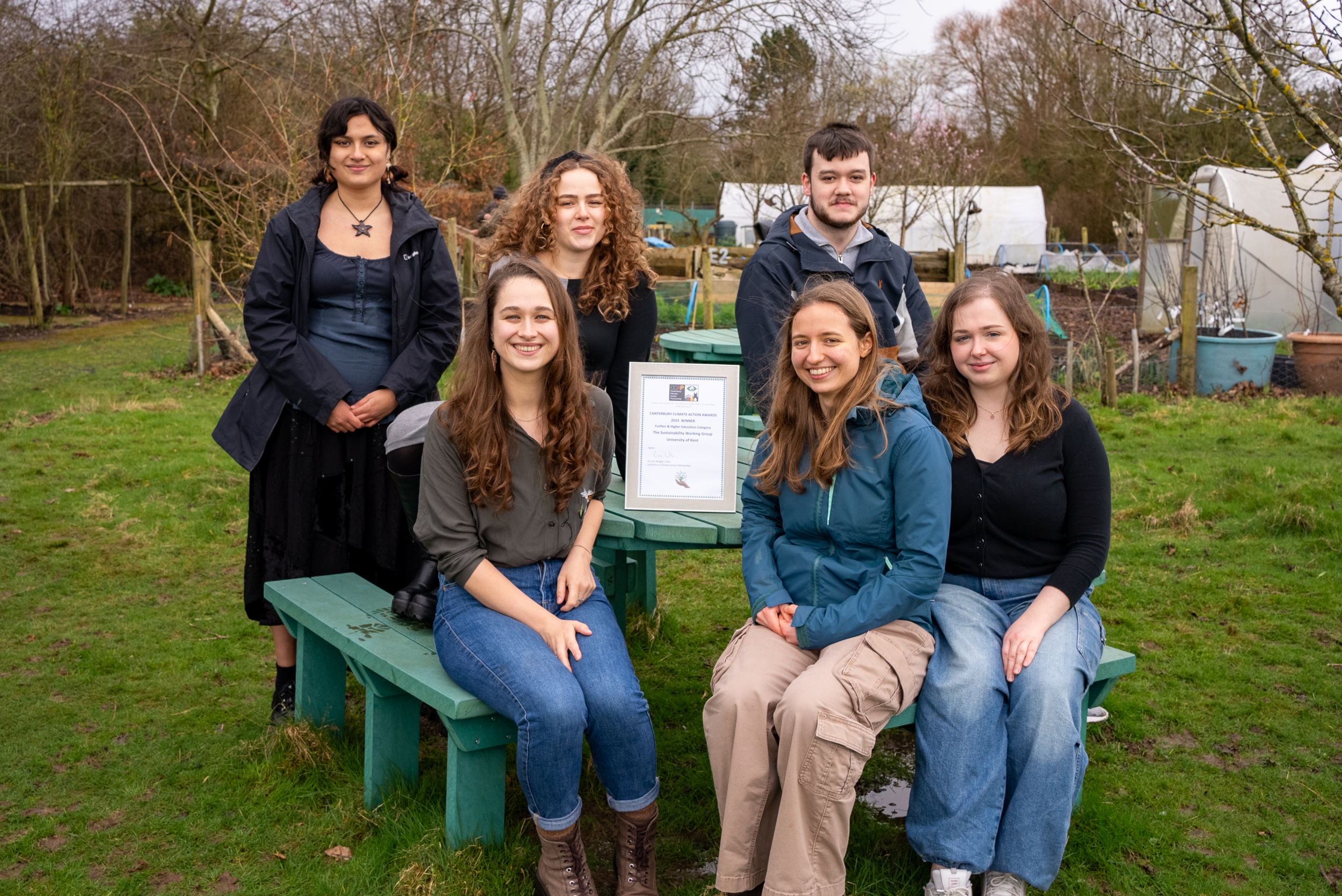 Sustainability Working Group sat on bench smiling with their Climate Action Award